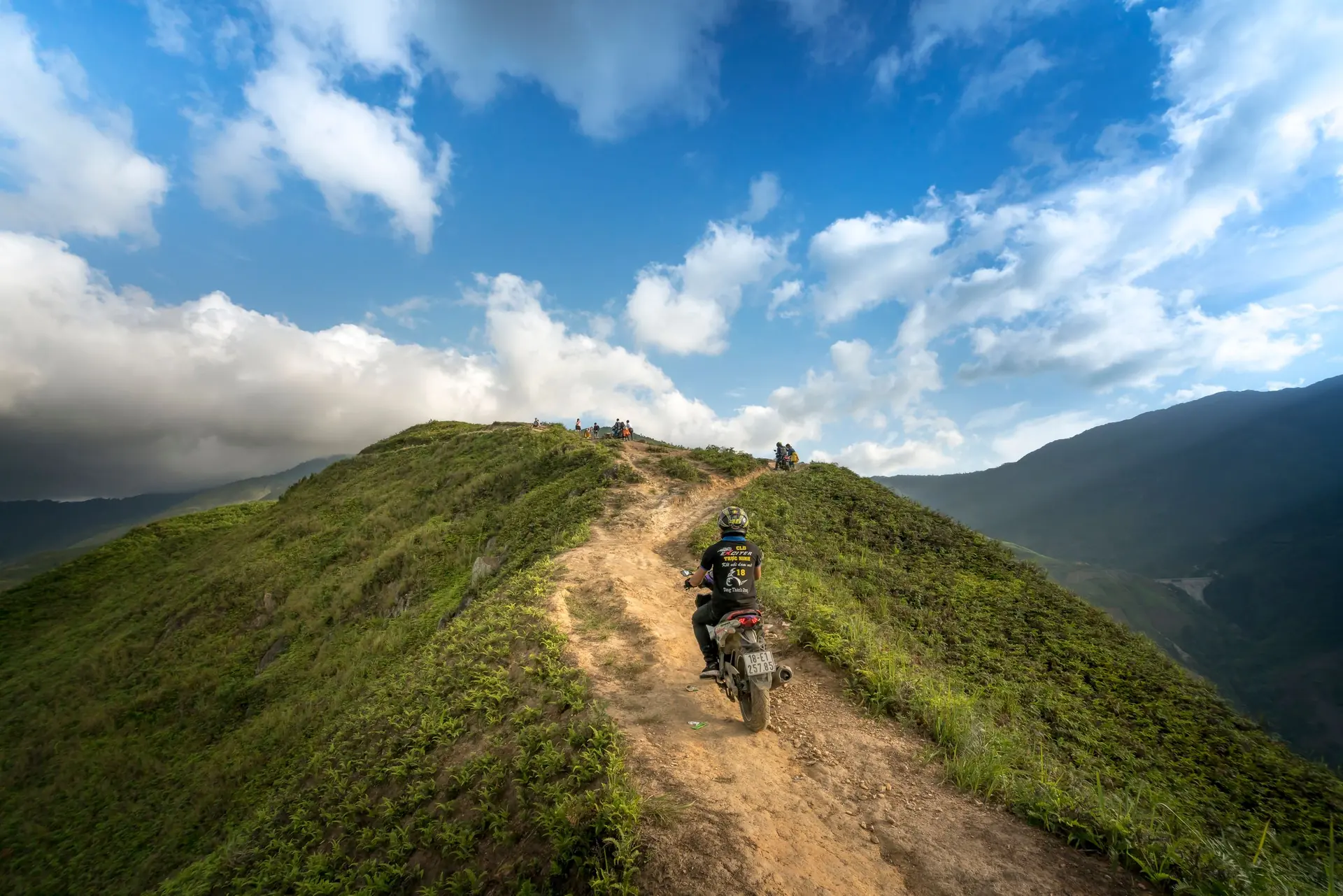 Người lái xe máy đi trên sống núi cỏ xanh ở Hà Giang