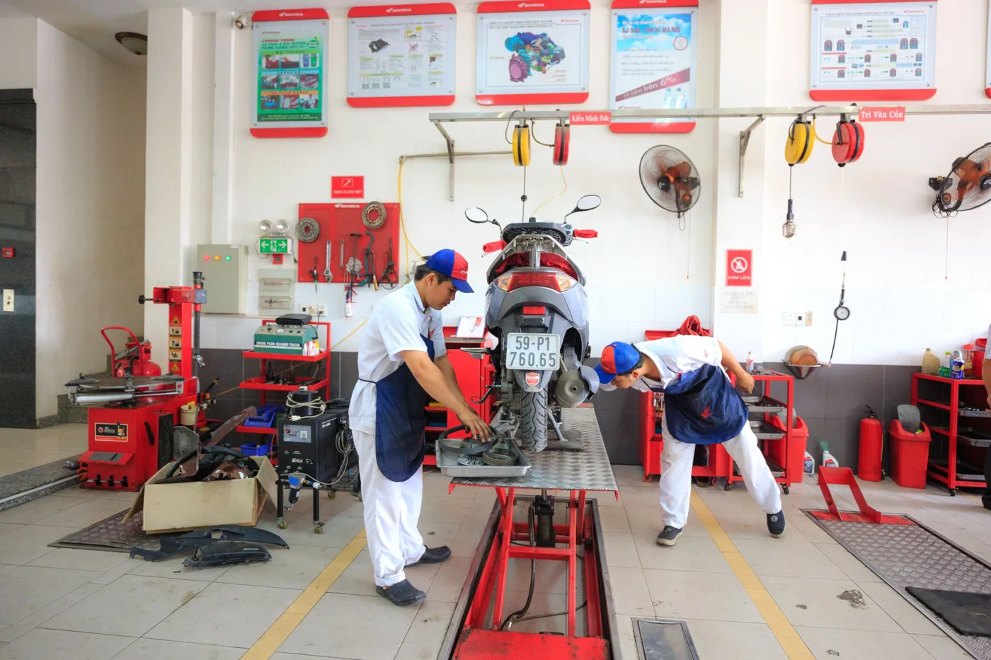 Thợ máy bảo dưỡng xe tay ga trên bàn nâng trong xưởng